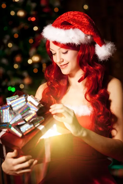 Jonge mooie lachende santa vrouw in de buurt van de kerstboom met — Stockfoto