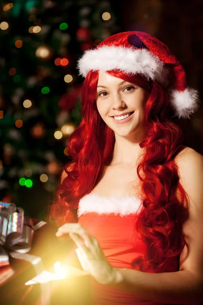 Junge schöne lächelnde Weihnachtsfrau in der Nähe des Weihnachtsbaums mit — Stockfoto