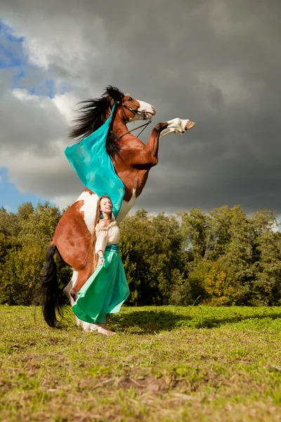 Bella donna con un cavallo nel campo. Ragazza in una fattoria con un — Foto Stock