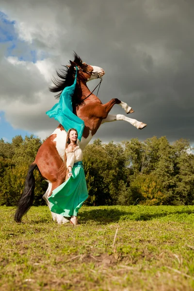 Uma mulher bonita com um cavalo no campo. Menina em uma fazenda com um — Fotografia de Stock