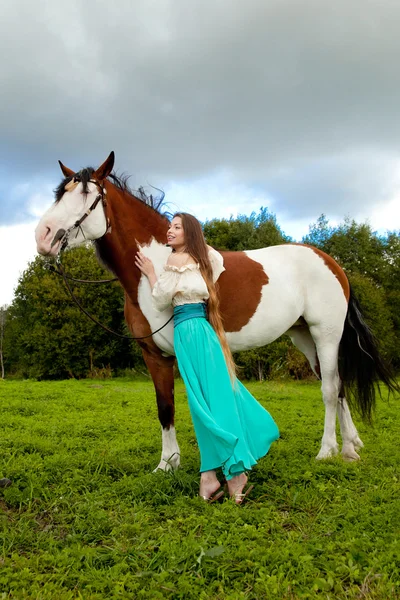 Hermosa mujer con un caballo en el campo. Chica en una granja con un — Foto de Stock