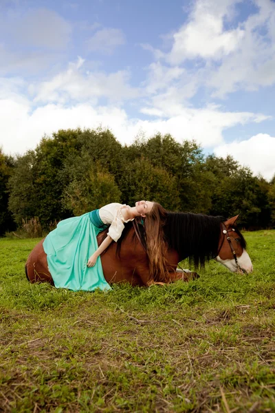 Vacker kvinna med en häst i fältet. flicka på en gård med en — Stockfoto
