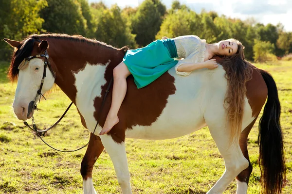 Uma mulher bonita com um cavalo no campo. Menina em uma fazenda com um — Fotografia de Stock