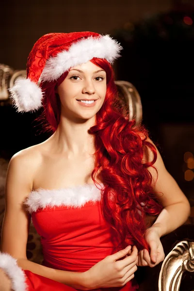 Νεαρή όμορφη χαμογελαστό santa γυναίκα κοντά το χριστουγεννιάτικο δέντρο. Gir Εικόνα Αρχείου