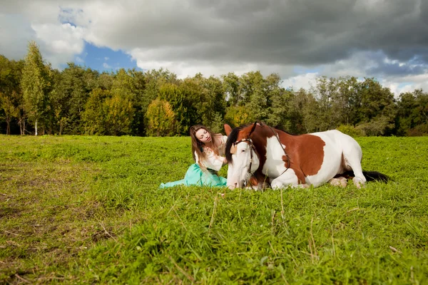Uma mulher bonita com um cavalo no campo. Menina em uma fazenda com um Fotografia De Stock