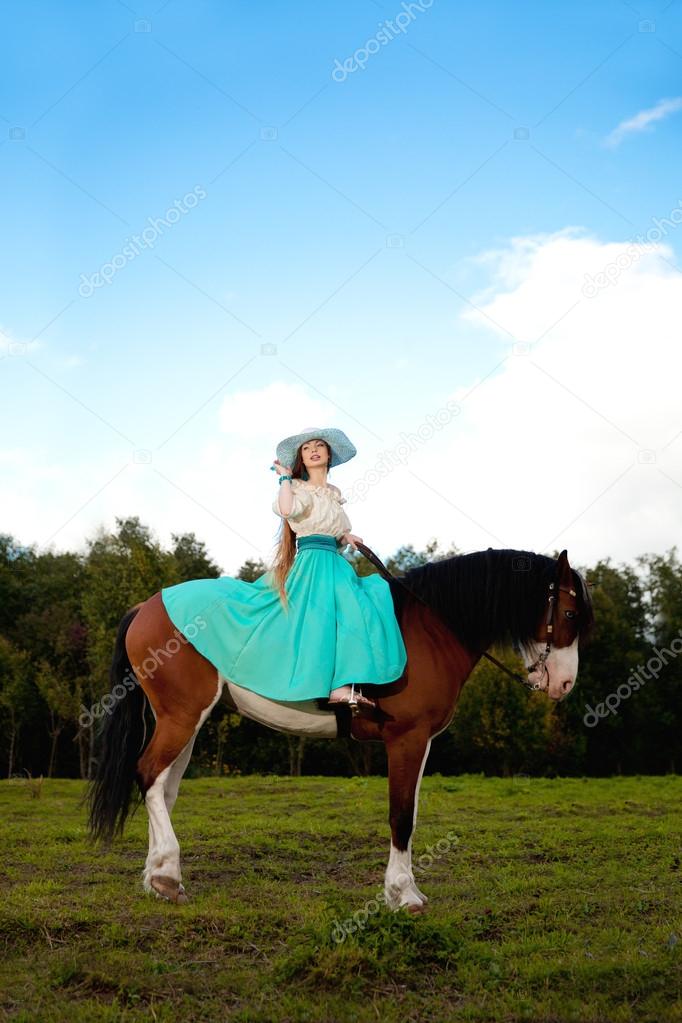 Beautiful woman with a horse in the field. Girl on a farm with a