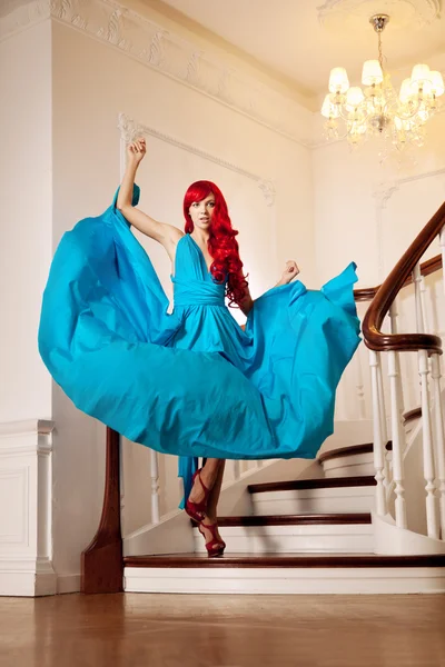 Mujer joven con lujoso pelo rojo largo y hermoso en un fas azul —  Fotos de Stock