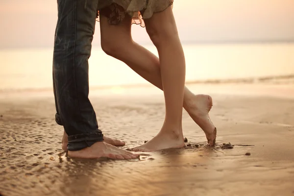 Una joven pareja cariñosa abrazándose y besándose en la playa. Amantes m — Foto de Stock