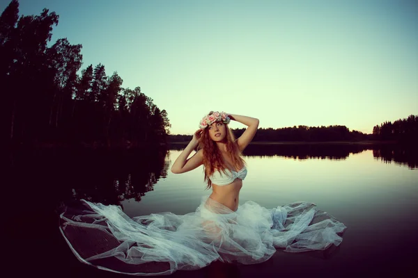 在夜间的湖中有美丽的女人。在日落时在湖中的女孩. — 图库照片