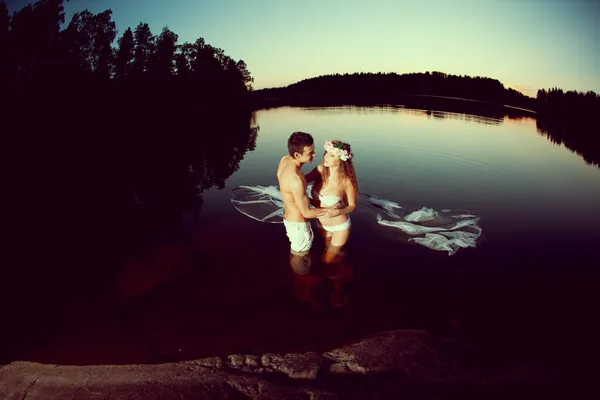 Dos amantes en un lago por la noche. Chica y hombre al atardecer en el lak — Foto de Stock