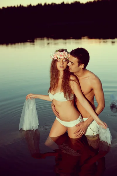 Dva milenci v jezeře v noci. dívka a muž při západu slunce v lak — Stock fotografie