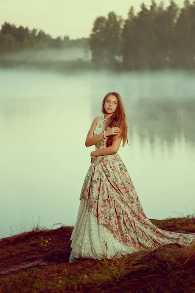 Donna di lusso in una foresta in un abito lungo vintage vicino al lago . — Foto Stock