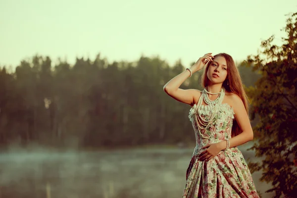 Mulher de luxo em uma floresta em um vestido vintage longo perto do lago . — Fotografia de Stock