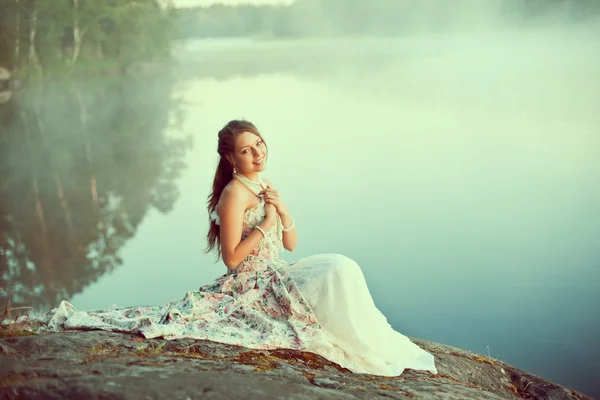 Mujer de lujo en un bosque en un largo vestido vintage cerca del lago . —  Fotos de Stock