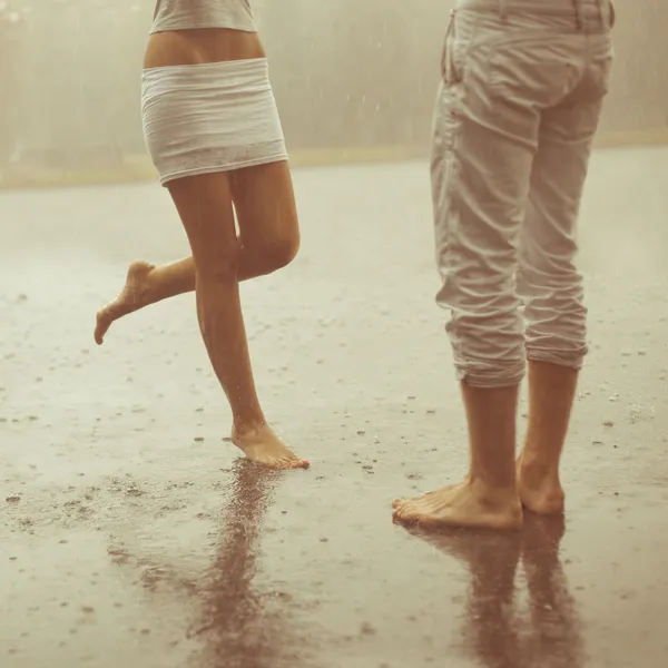 Ein liebevolles junges Paar, das sich im Regen umarmt und küsst. Liebhaber m Stockbild