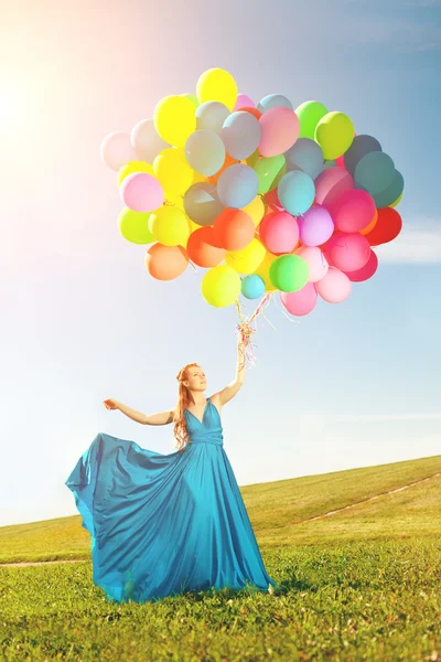 Mujer de moda de lujo con globos en la mano en el campo contra —  Fotos de Stock