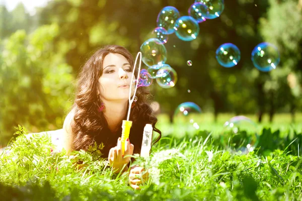 Woman and soap bubbles in park. Beautiful young girl lying on th — Stock Photo, Image