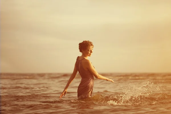 Mujer en la playa al atardecer. — Foto de Stock