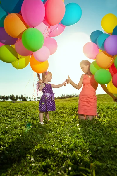 Красива маленька дівчинка з материнськими кольоровими кульками і веселкою Ліцензійні Стокові Фото