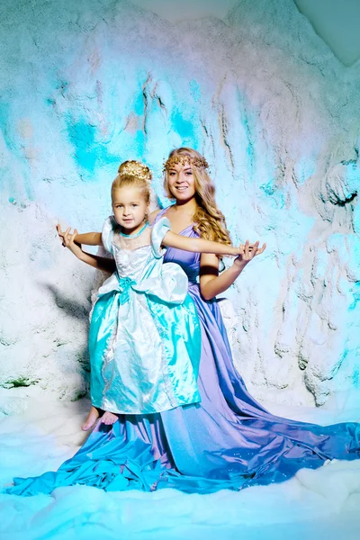 Petite fille avec mère en robe de princesse sur un fond de w Photo De Stock