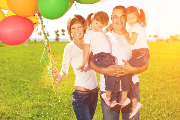 Famiglia felice che tiene palloncini colorati. Mamma, ded e due daughte Immagine Stock