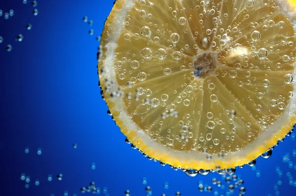 Scheibe frische Zitrone in Wasser mit Luftblasen — Stockfoto