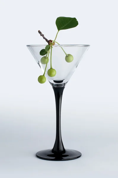 Незрелая зеленая вишня в бокале мартини — стоковое фото
