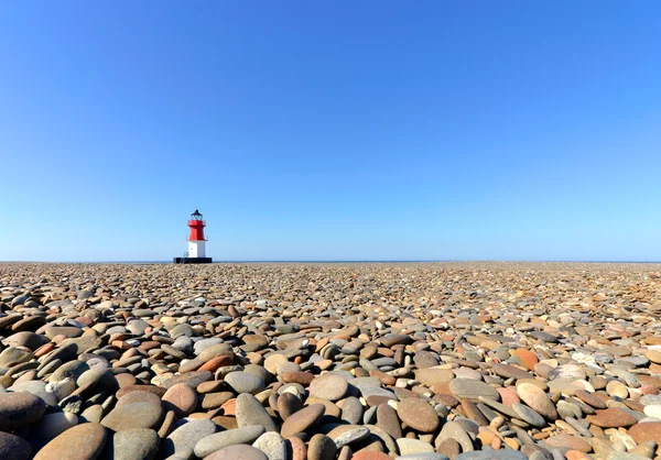 Faro con spiaggia di ciottoli in primo piano — Foto Stock