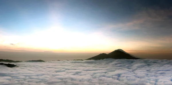 Zonsopgang boven wolken met een vulkaan bergzicht — Stockfoto