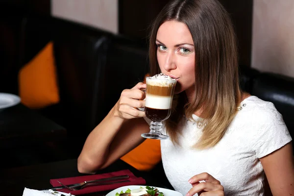 Söt ung kvinna sitter i caféet med en kopp kaffe — Stockfoto