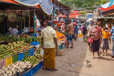 KANDY, SRI LANKA - 20 Mart Sri Lanka 'daki Kandy Market' te meyve tezgahlarının önünde yürüyen insanlar