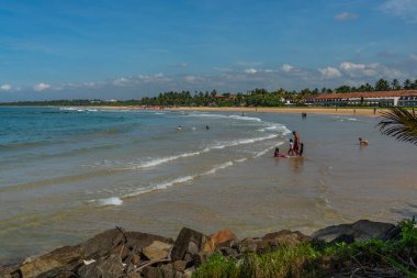BENTOTA, SRI LANKA - HAZİRAN 02.2021 Kıyı ve okyanusta insanlar, Hint Okyanusu Bentorta Sahili, Sri Lanka