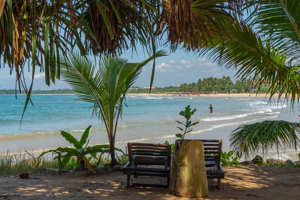 ベントタビーチの日陰にある2つのベンチ スリランカのインド洋 海岸の背景の人々 — ストック写真