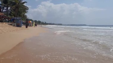 HIKKADUWA, SRI LANKA - 21 HAZİRAN 2022: Hikkaduwa plajında yürüyen insanlar