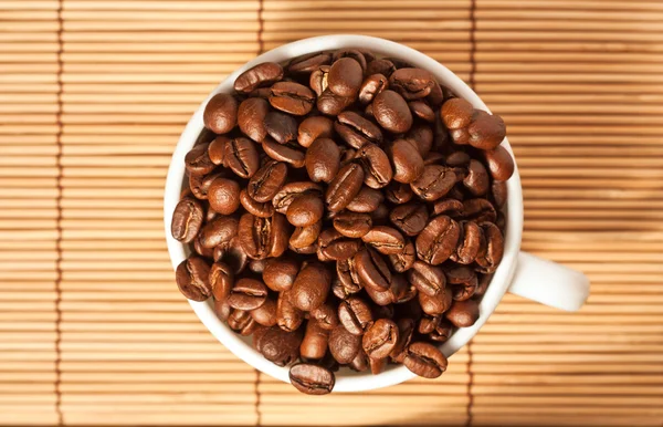 Chávena cheia com grãos de café na mesa — Fotografia de Stock