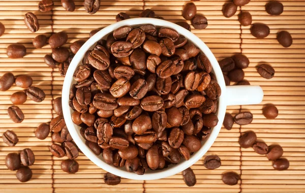 White cup with coffee beans on the table — Stock Photo, Image