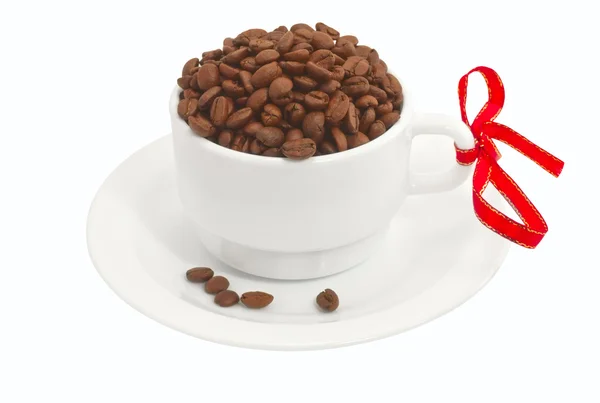 Біла чашка, повна кавових зерен з червоною стрічкою — стокове фото