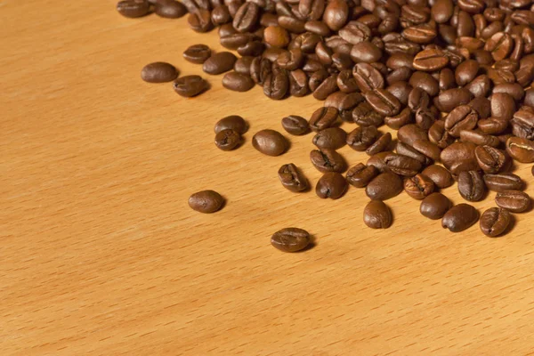 Veel koffie bonen op houten tafel — Stockfoto