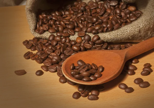 Gebrande koffiebonen in een zak met een houten lepel — Stockfoto