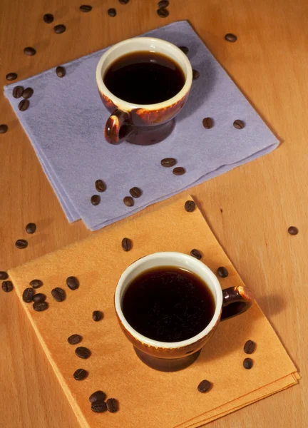 Duas xícaras de café em guardanapos com grãos de café — Fotografia de Stock