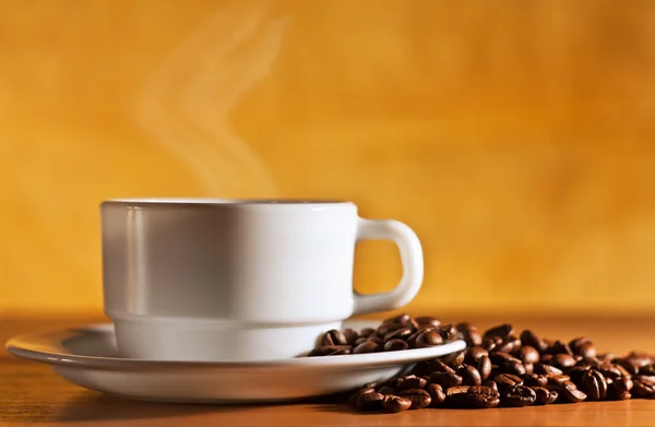 Tazza bianca di caffè caldo con vapore è sul tavolo — Foto Stock