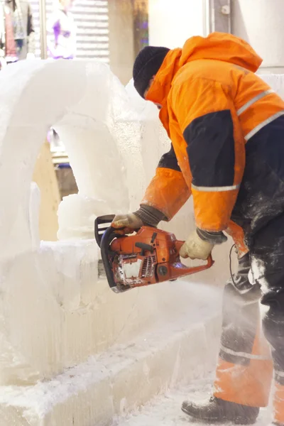 Worker carves figures out of ice