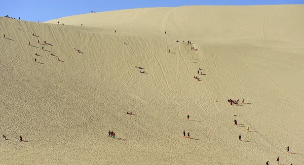 Туристы поднимаются по песчаным дюнам — стоковое фото