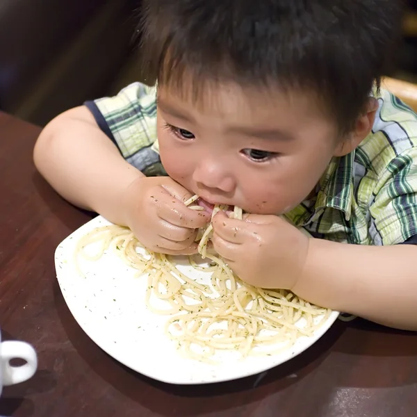 Comer bebê para pegar macarrão com a mão — Fotografia de Stock