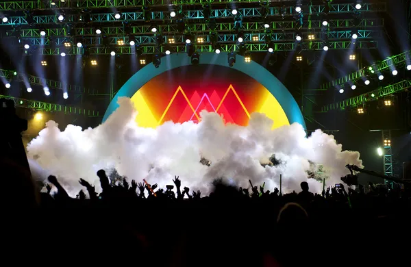 Siluetas de la multitud de conciertos de música en vivo frente a luces de escenario brillantes —  Fotos de Stock