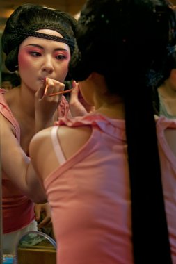 Chinese opera actress painting face at backstage