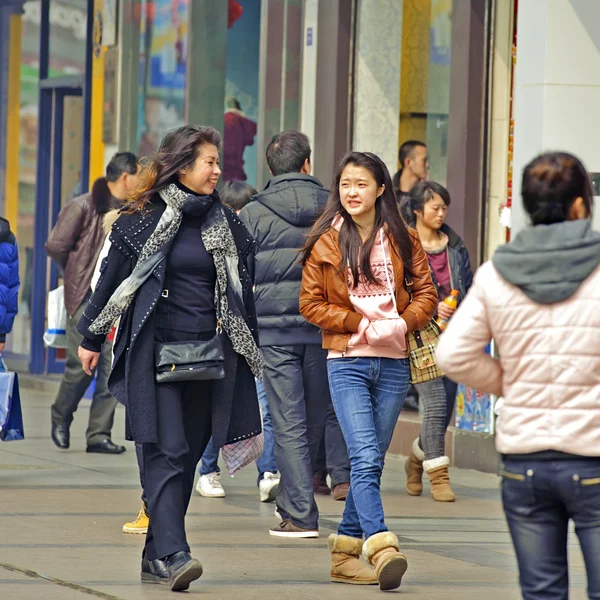 Due ragazze passano attraverso una trafficata via pedonale dello shopping — Foto Stock