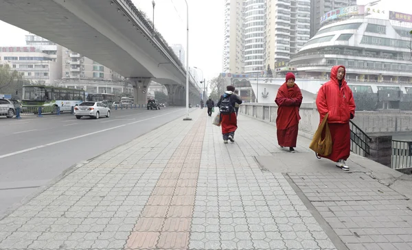 Tibet monk kentsel yolda yürürken kırmızı kadın kıyafeti giymiş — Stok fotoğraf