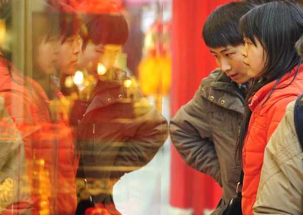 A woman and man stop to look in the window of a gold shop — Stock Photo, Image