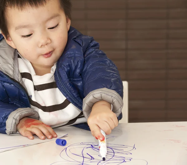 Een schattige baby is schilderen op tafel — Stockfoto